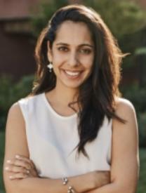 Professional headshot of Dr. Hashmi in a white sleeveless top with her arms crossed. 